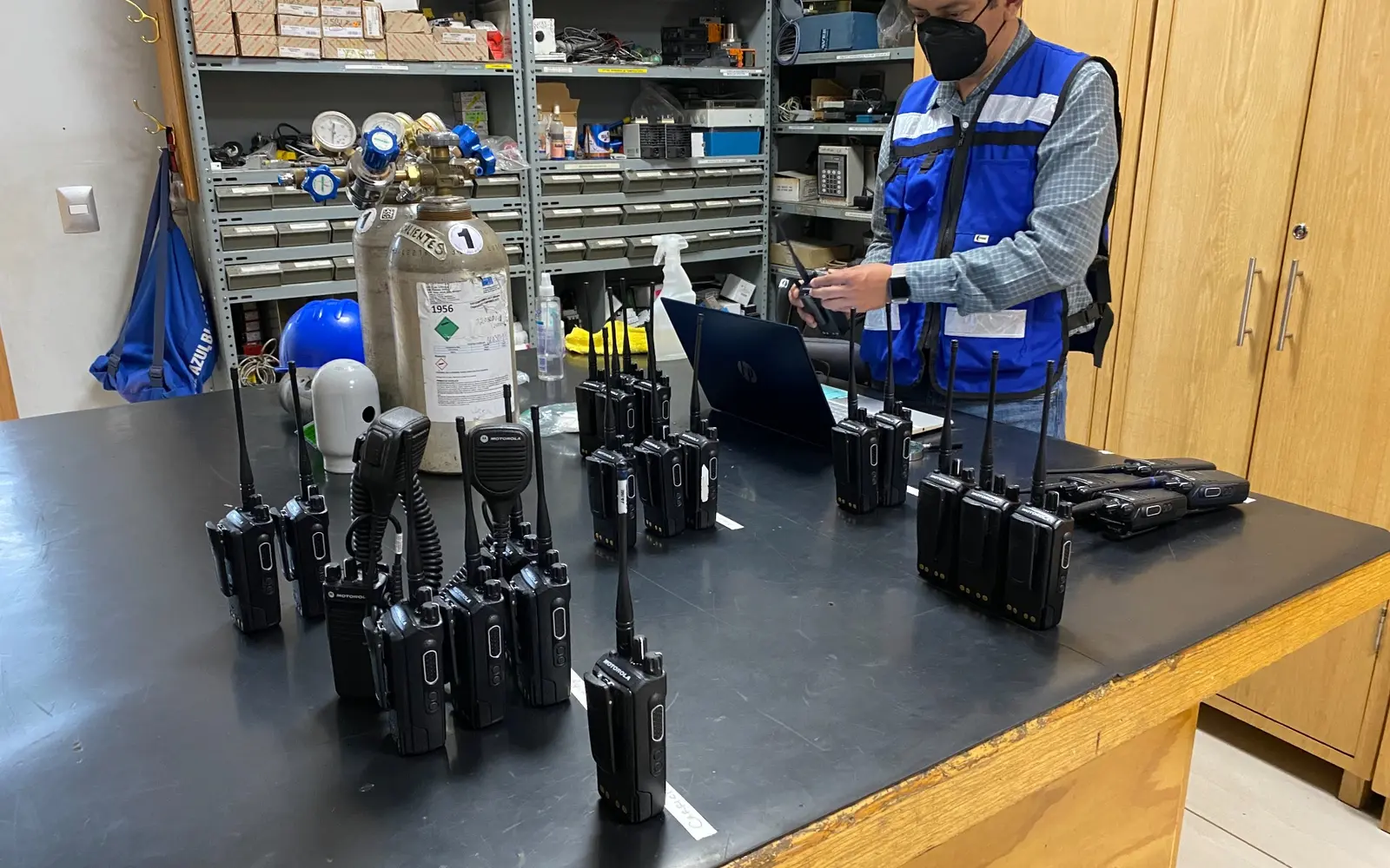 Técnico de WTI comm revisando un conjunto de radios portátiles en una mesa de servicio